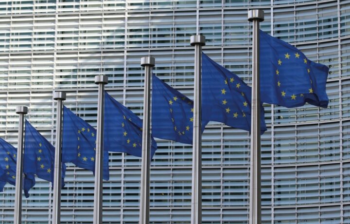 Zastave EU pred Evropsko komisijo v Bruslju simbolizirajo evropsko institucionalno moč, ki pa je zaradi odvisnosti od ZDA omejena na vseh ključnih področjih.